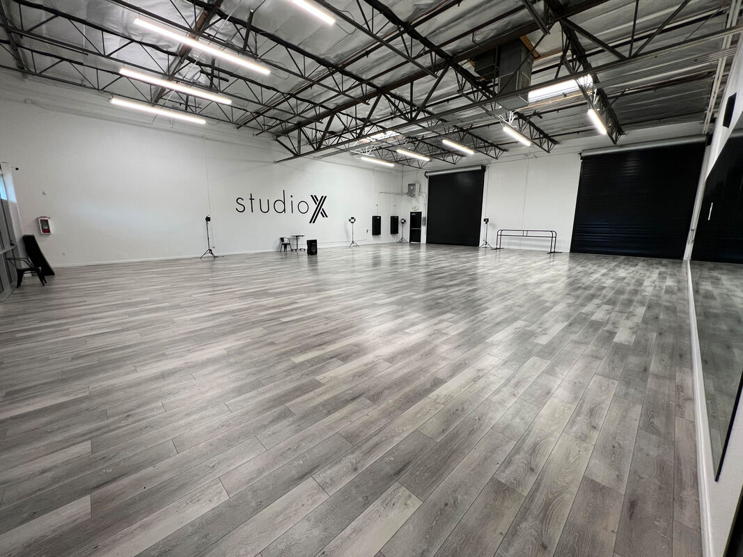 Spacious and modern dance studio, Studio X, designed by AtoZ Construction, featuring high ceilings, ample lighting, and professional-grade flooring.