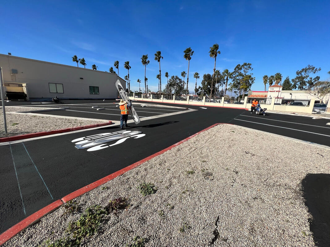 Construction crew from AtoZ Construction marking parking lot lines and symbols in a newly paved commercial parking area, demonstrating precision and professional quality.Picture