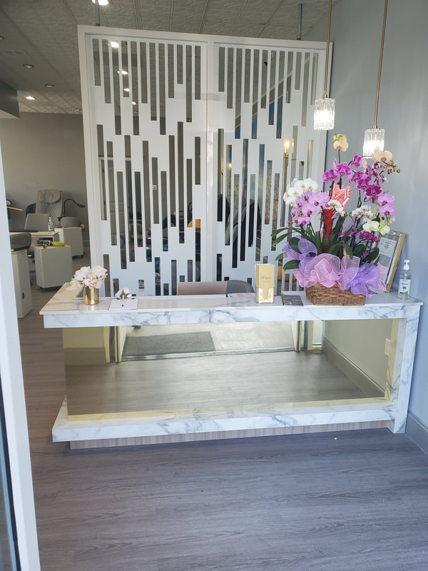 Elegant reception desk at a modern nail salon designed by AtoZ Construction, featuring a sleek marble countertop, stylish decor, and welcoming floral arrangement.Picture