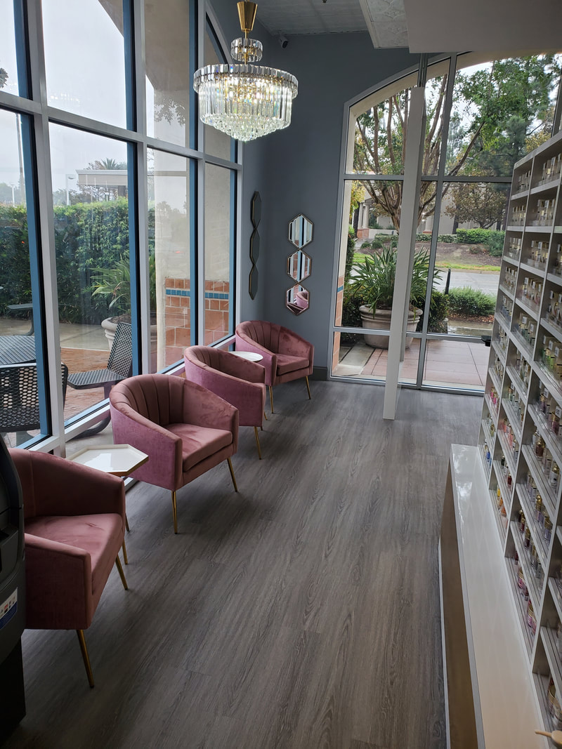 Chic waiting area at a modern nail salon designed by AtoZ Construction, featuring plush pink chairs, large windows, and elegant chandeliers for a welcoming atmosphere.Picture