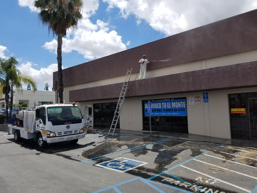 Construction worker from AtoZ Construction power washing the exterior of a commercial building, demonstrating attention to detail and professional maintenance services.