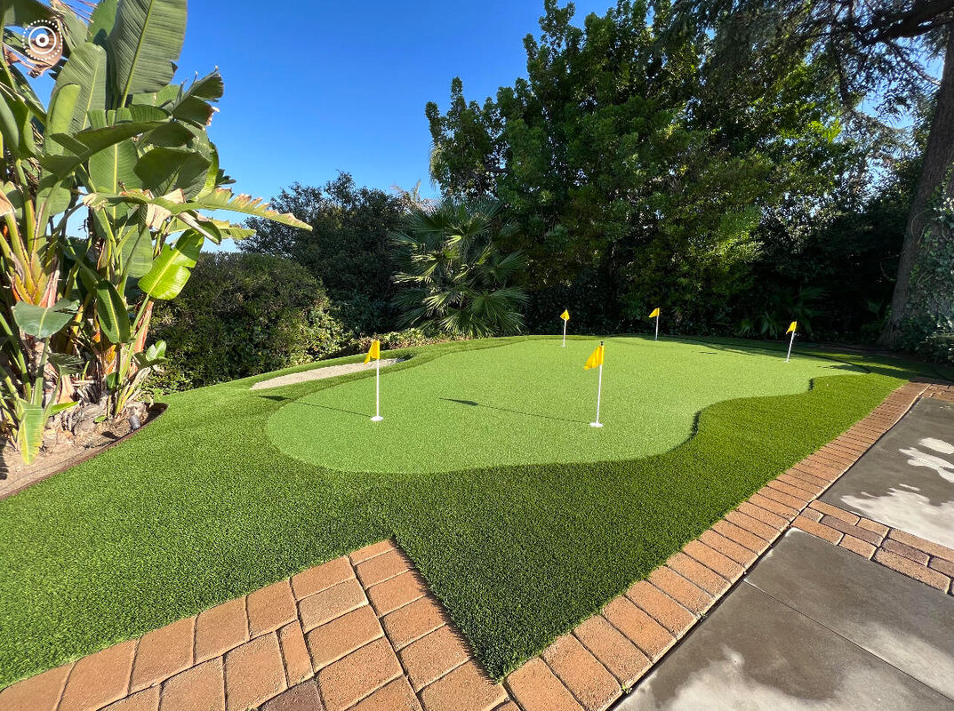 Beautiful backyard putting green designed by AtoZ Construction, featuring lush landscaping and a professionally installed turf.